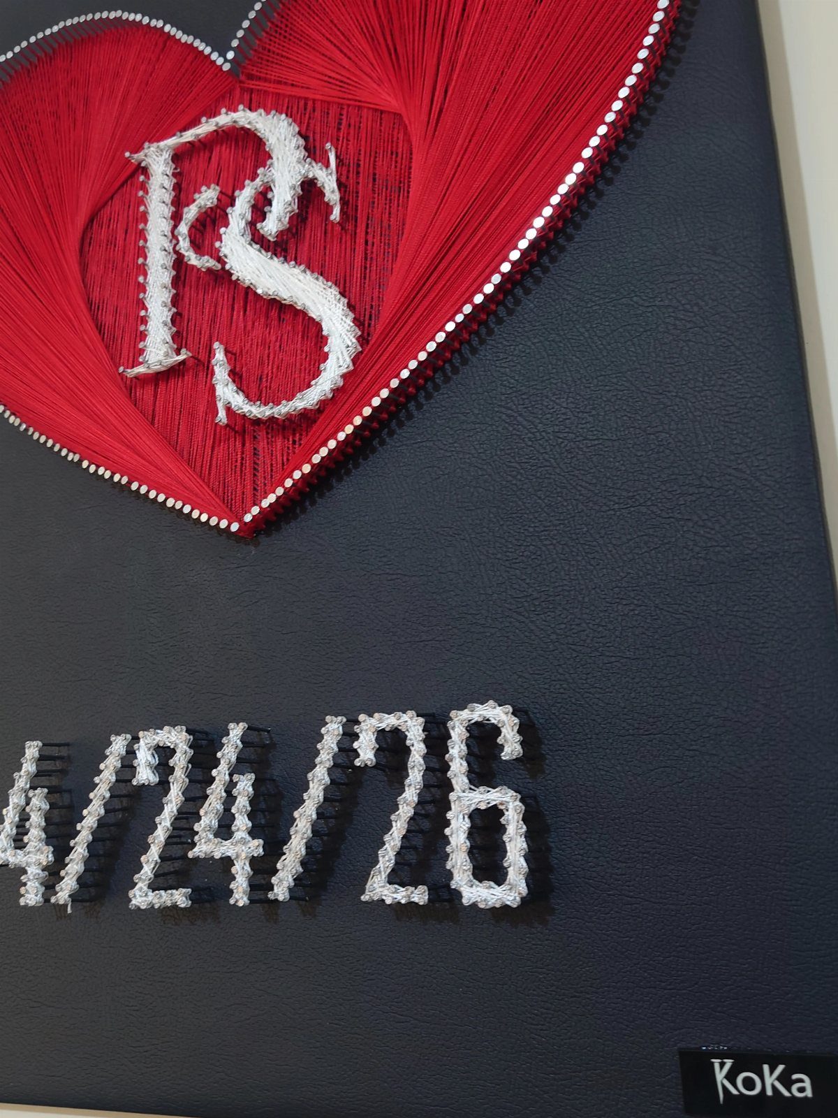 String art heart with white initials and a date on black background