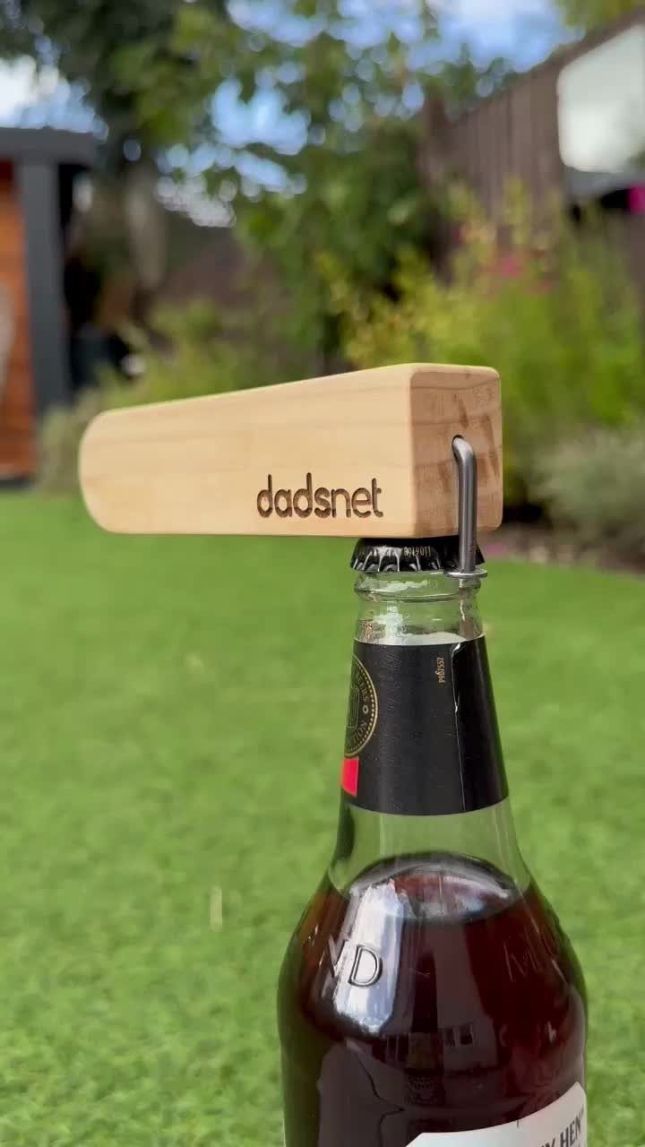 Wooden bottle opener with engraved text resting on top of a glass beer bottle