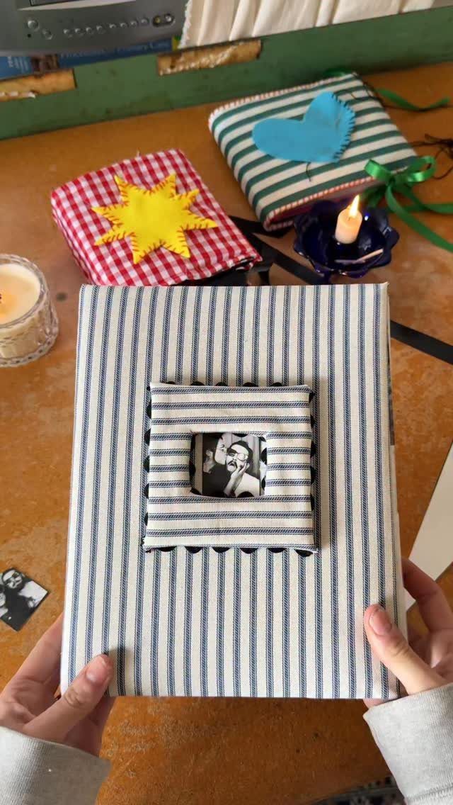 Handmade photo album with blue striped fabric cover and a small photo window.