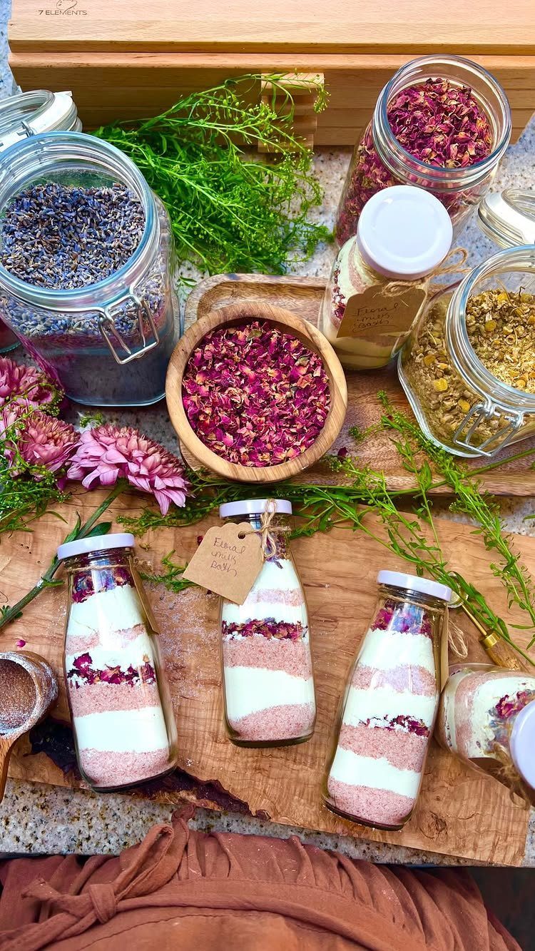 Layered pink and white bath salts in glass bottles with dried flower petals.