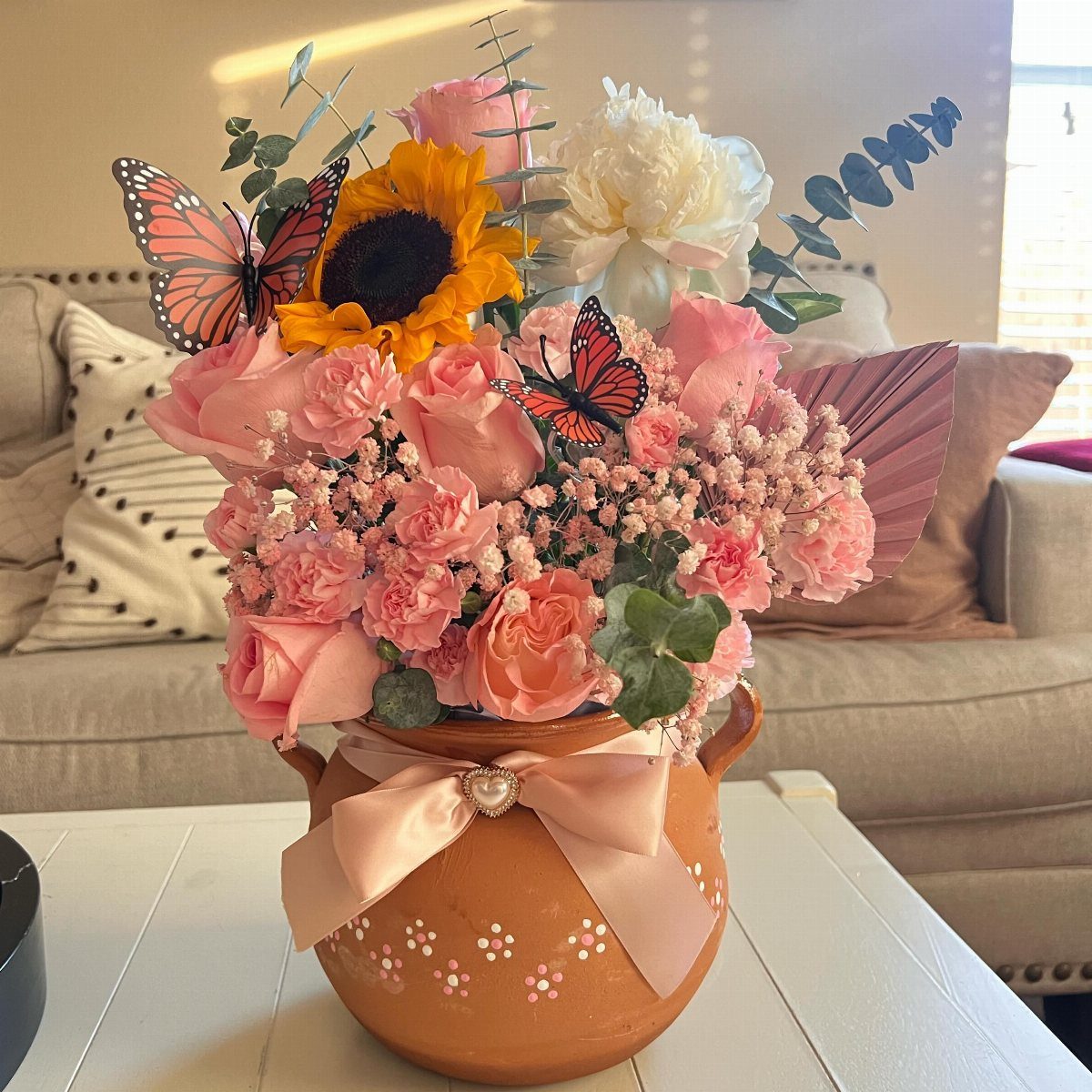 Decorated terracotta pot with white dots and pink bow holding a colorful flower bouquet.