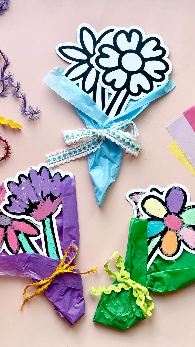 Three paper flower bouquets wrapped in colorful tissue paper on a pink background.