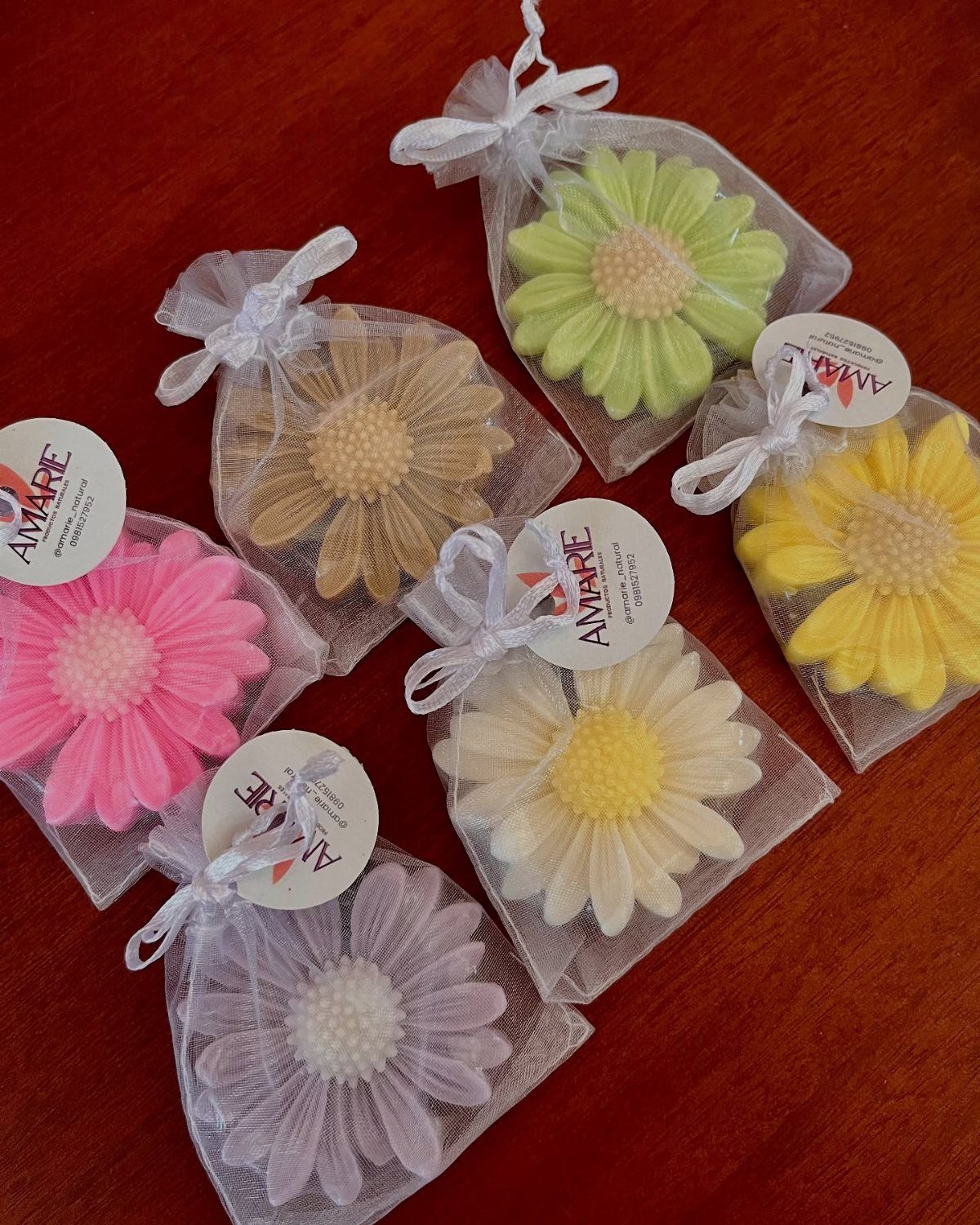 Flower-shaped soaps in colorful hues packaged in white mesh drawstring gift bags.