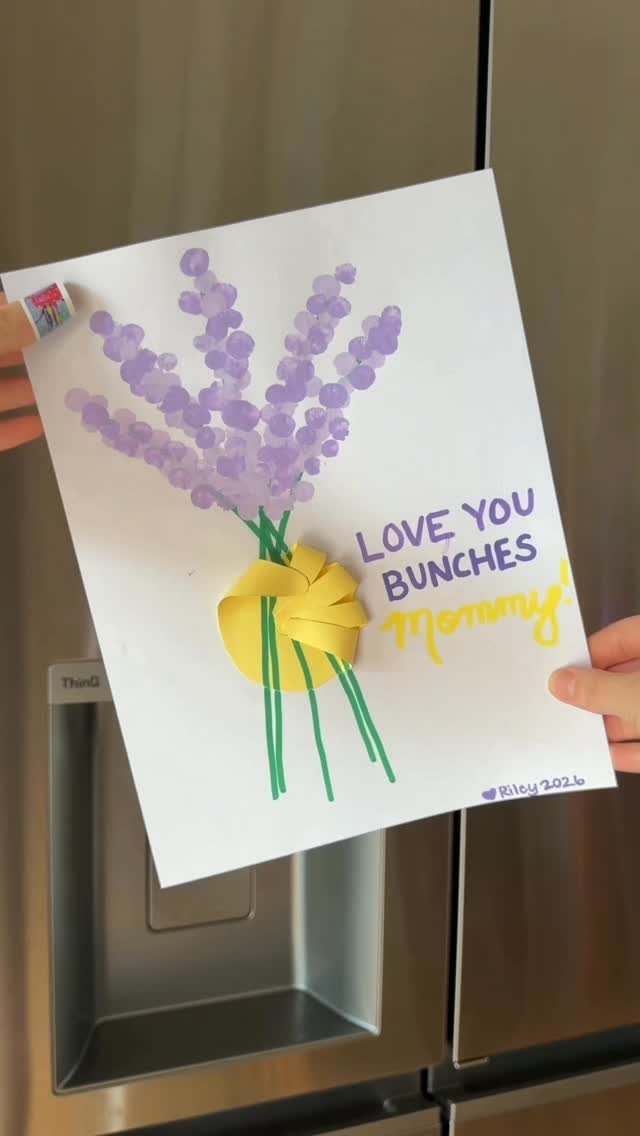 Handprint bouquet artwork with purple flowers and a yellow bow on white paper.