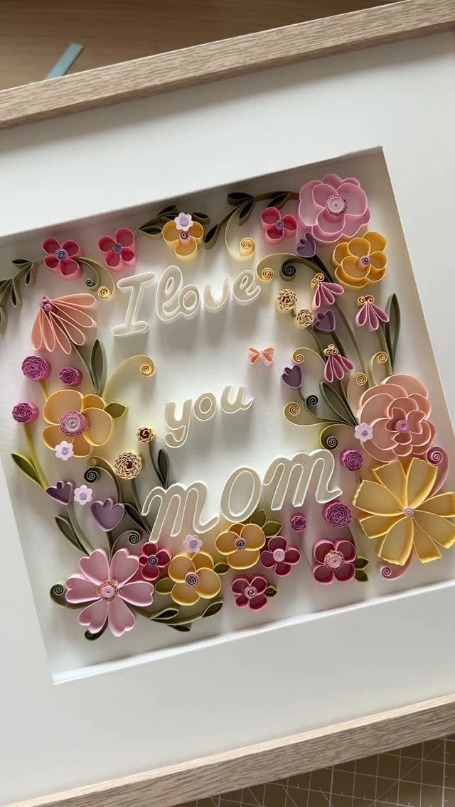 Quilled paper art with colorful flowers and the words I love you mom.