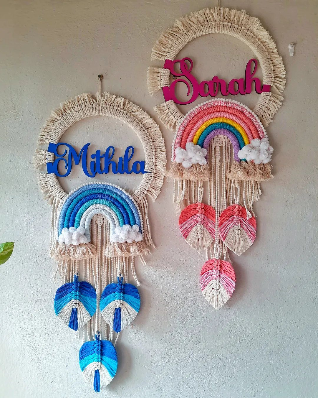 Two personalized macrame wall hangings featuring colorful yarn rainbows and hanging tassels.