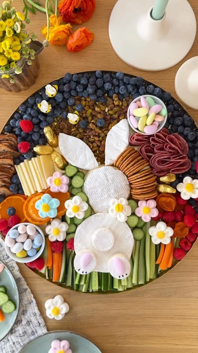 Bunny shaped snack board with fruit, vegetables, cheese, and candy eggs on platter.