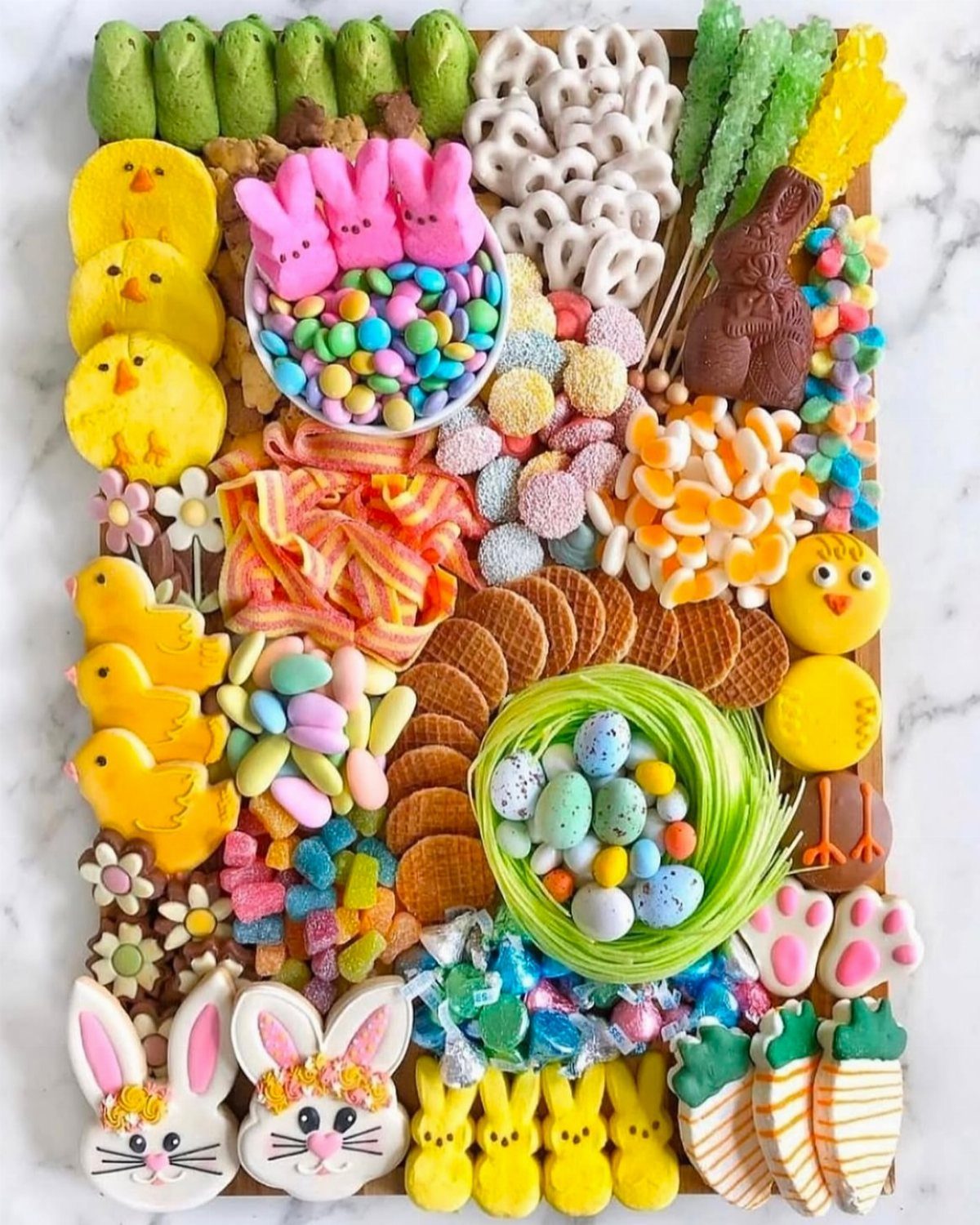 Easter candy board with chick cookies, chocolate bunny, and colorful pastel sweets.