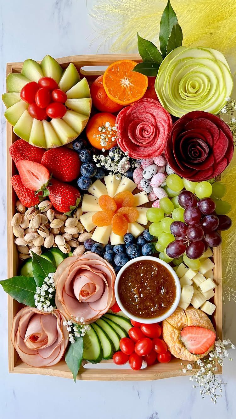 Wooden charcuterie tray with meat roses, fresh fruits, vegetables, and various cheeses.