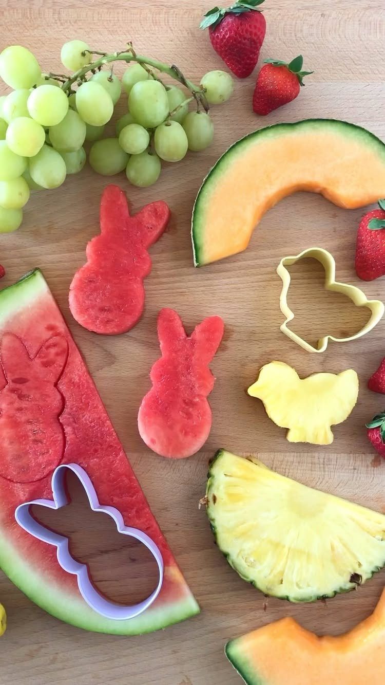 Watermelon bunny shapes and a pineapple chick beside cookie cutters on wooden board