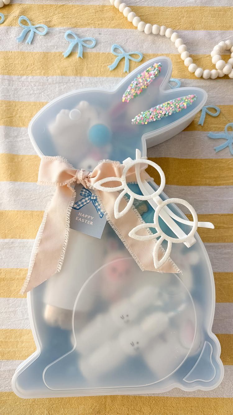 Bunny-shaped plastic container filled with Easter treats on a yellow striped background.