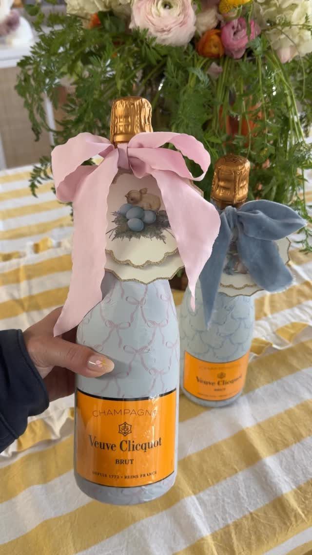 Wrapped champagne bottles with bunny illustrations and ribbons on a striped tablecloth