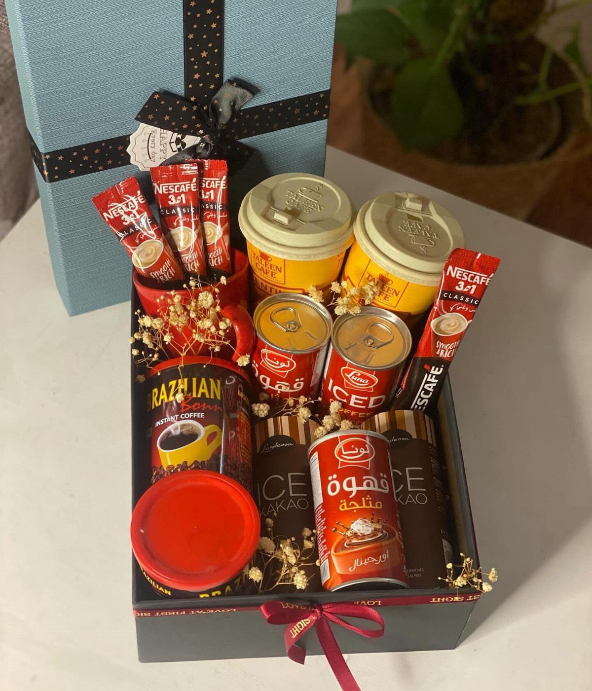 Coffee gift box containing various instant coffee brands, canisters, and dried white flowers.