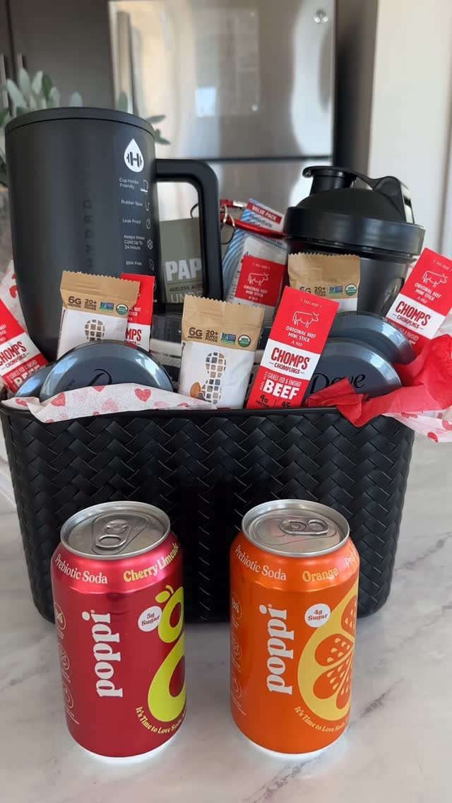 Black woven gift basket containing prebiotic sodas, beef jerky, and fitness water bottles.
