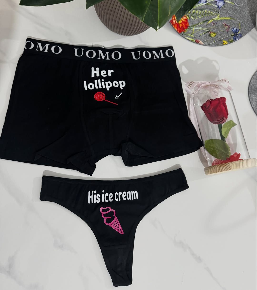 Matching black couple's underwear with humorous food graphics on a white marble background.