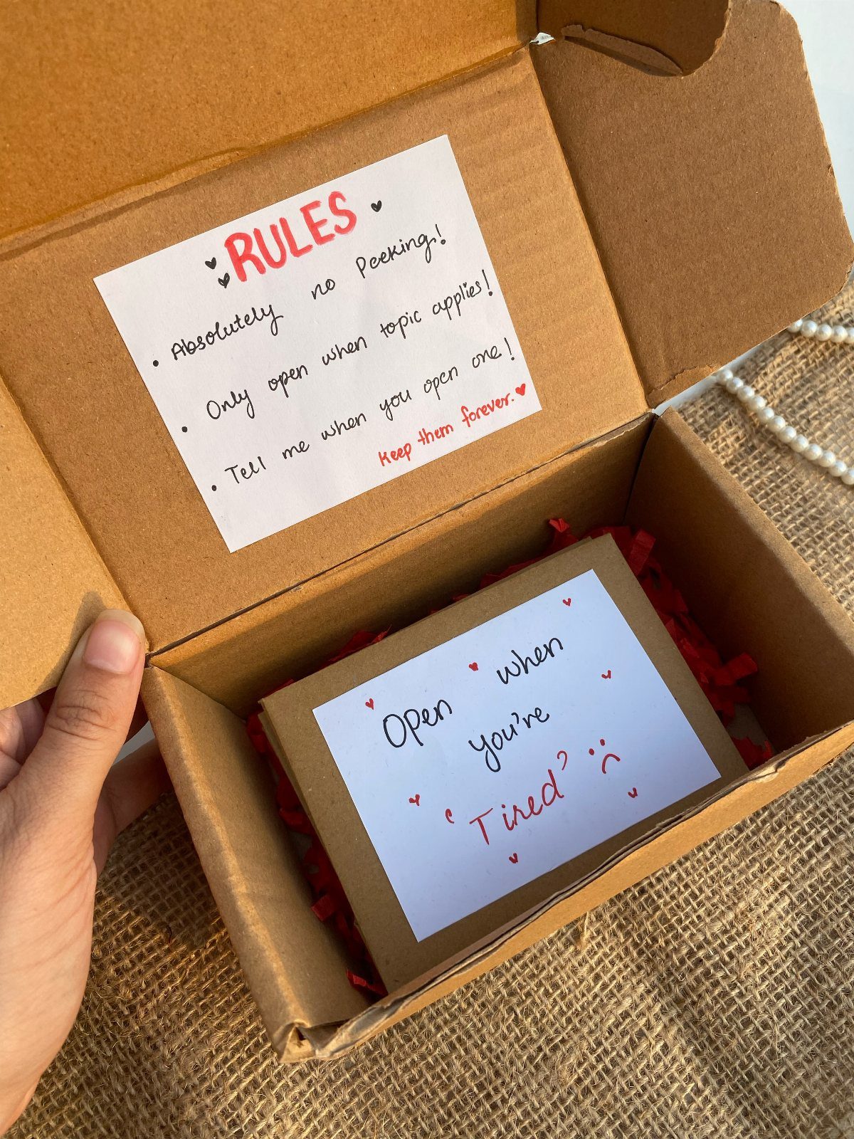 Open cardboard gift box with a personalized open when letter and red filler