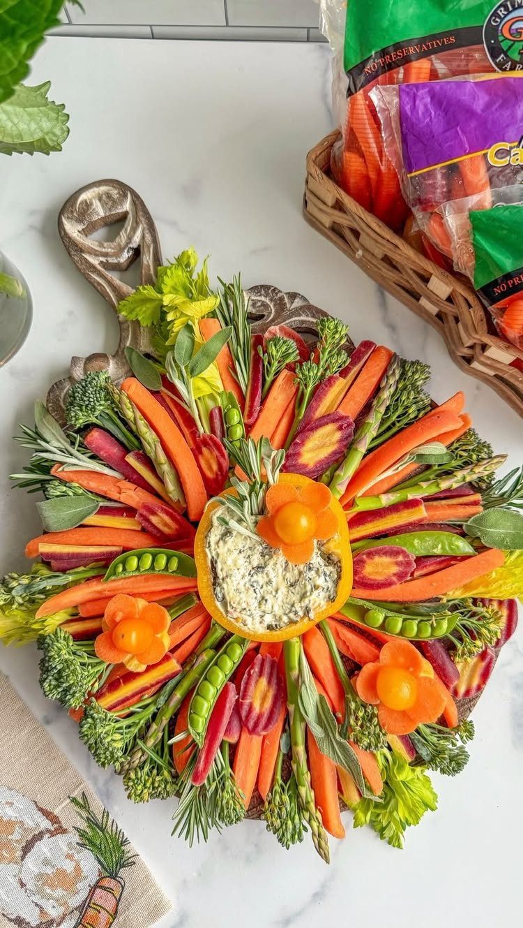 Colorful vegetable platter with carrots, broccoli, and snap peas around a dip bowl.