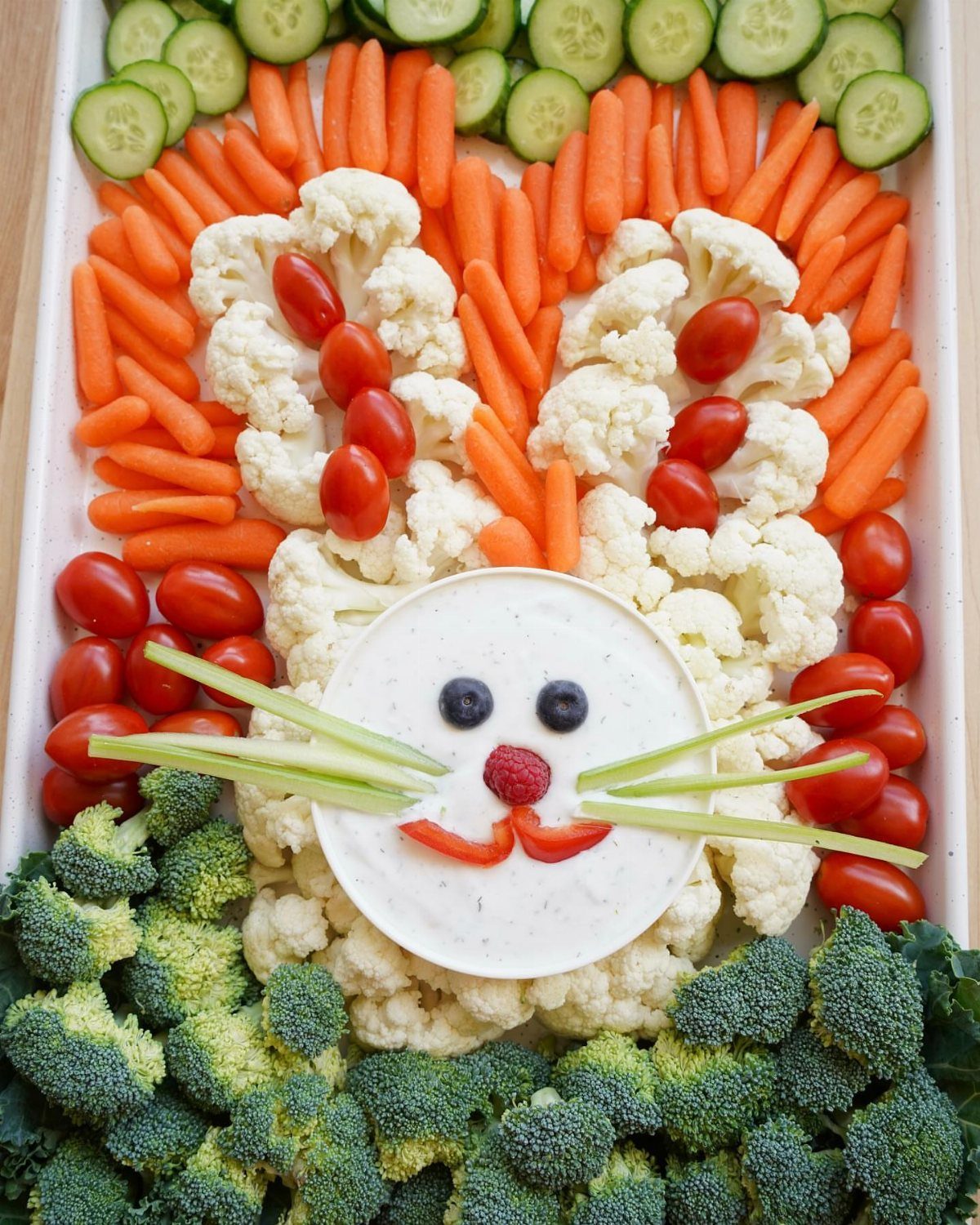Vegetable tray arranged as a bunny face with cauliflower, carrots, and broccoli.