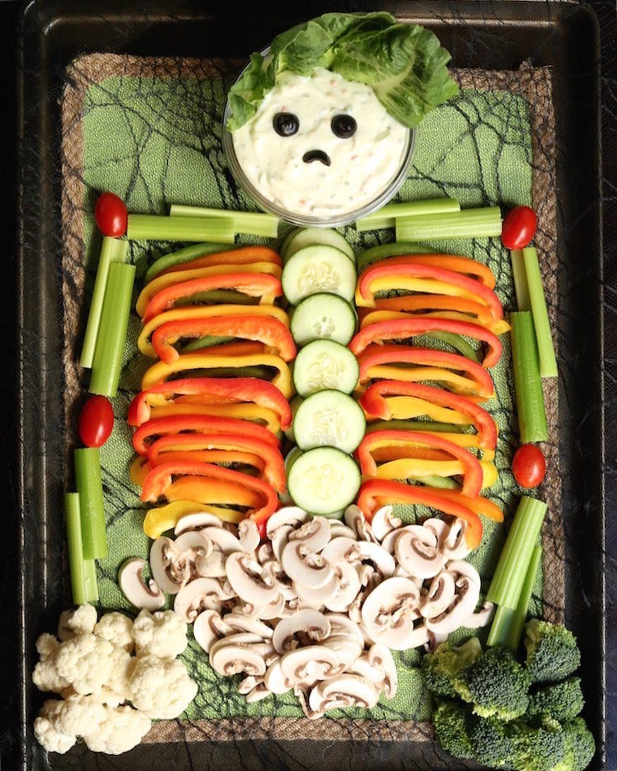 Skeleton veggie tray made from peppers, cucumbers, celery, mushrooms, and a dip bowl.
