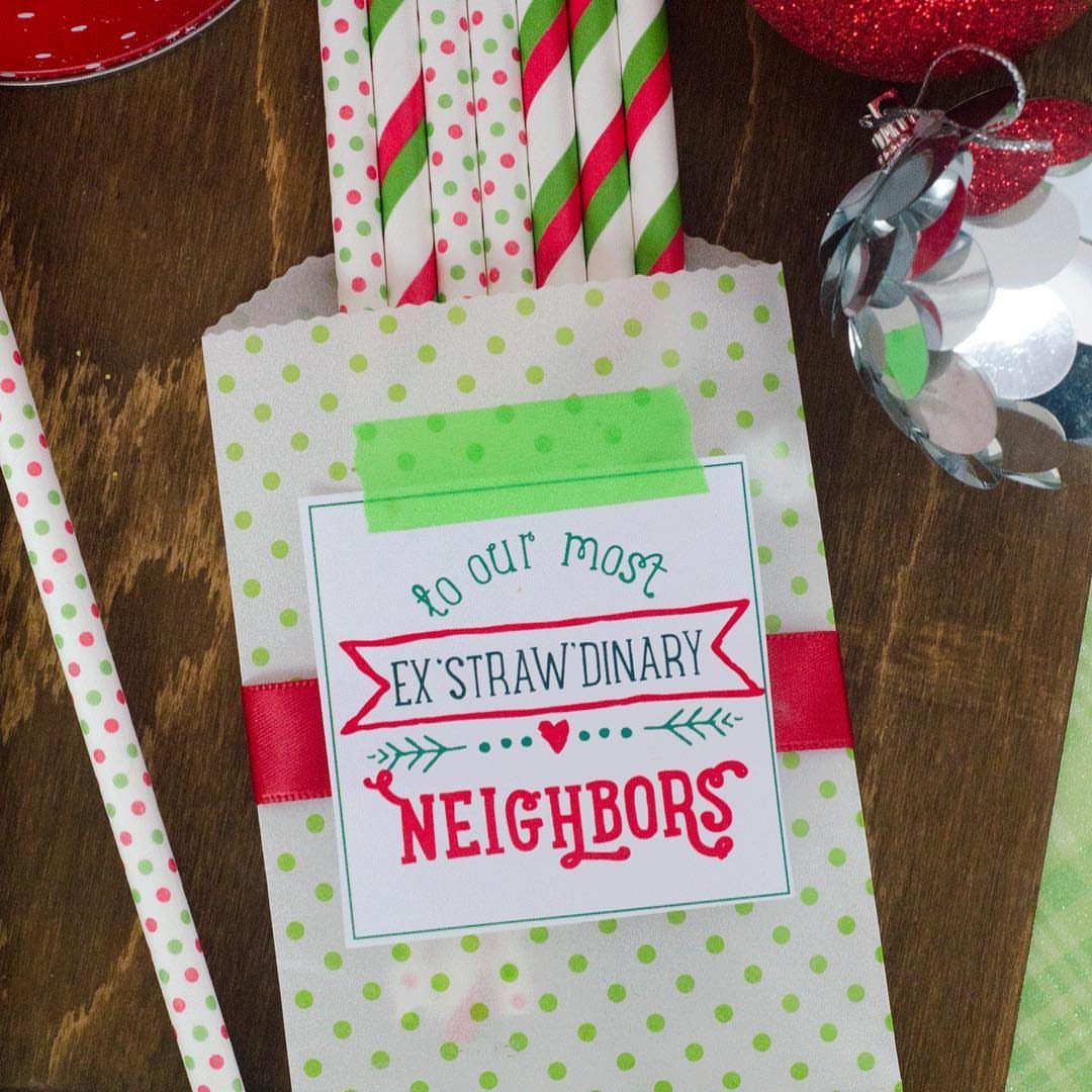 Gift bag with striped straws and a card for extraordinary neighbors on wood.