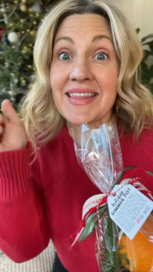 Woman in red sweater holding a homemade holiday simmer pot gift bag.