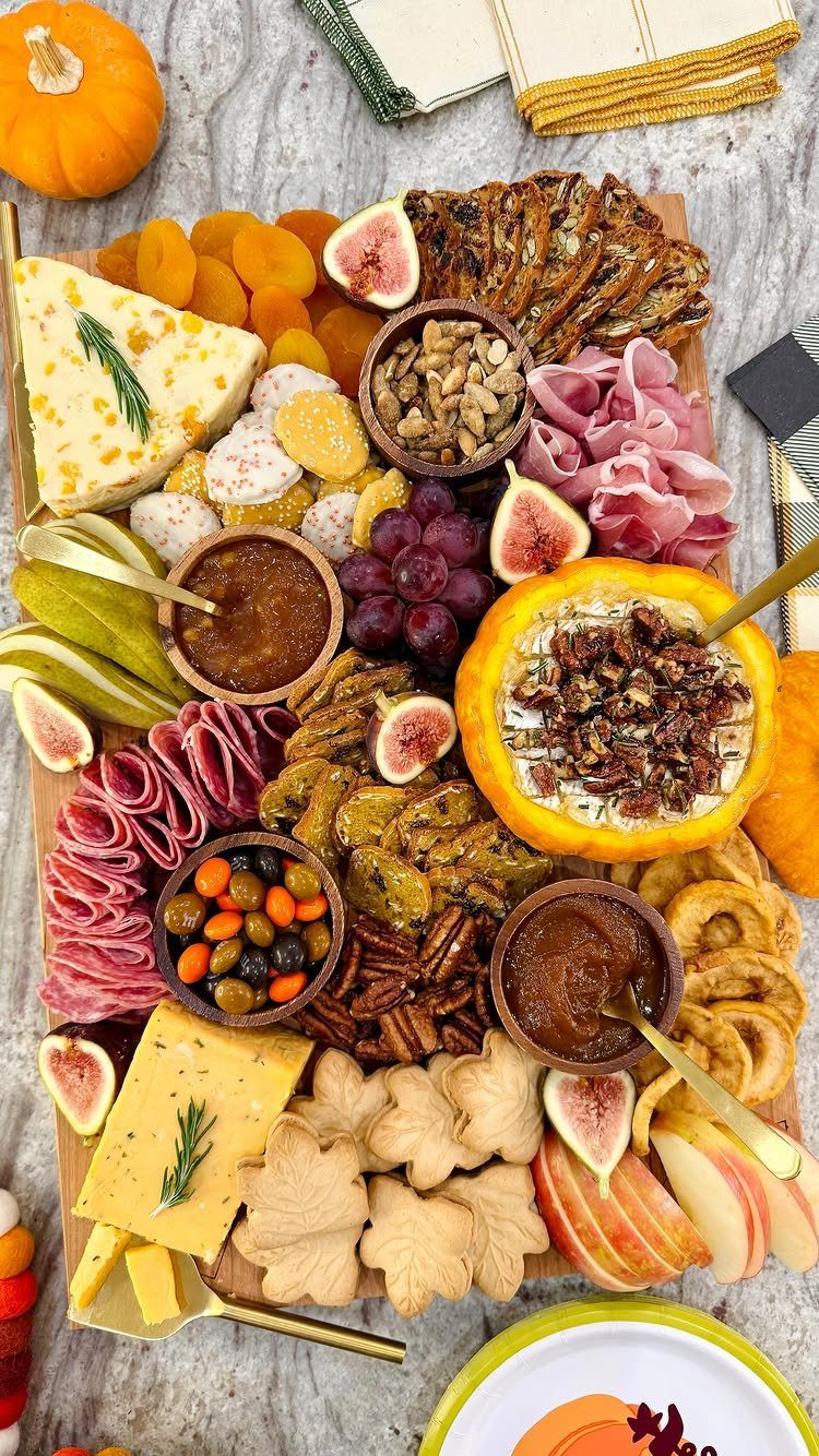 Charcuterie board with meats, cheeses, and a pumpkin bowl filled with creamy hummus.