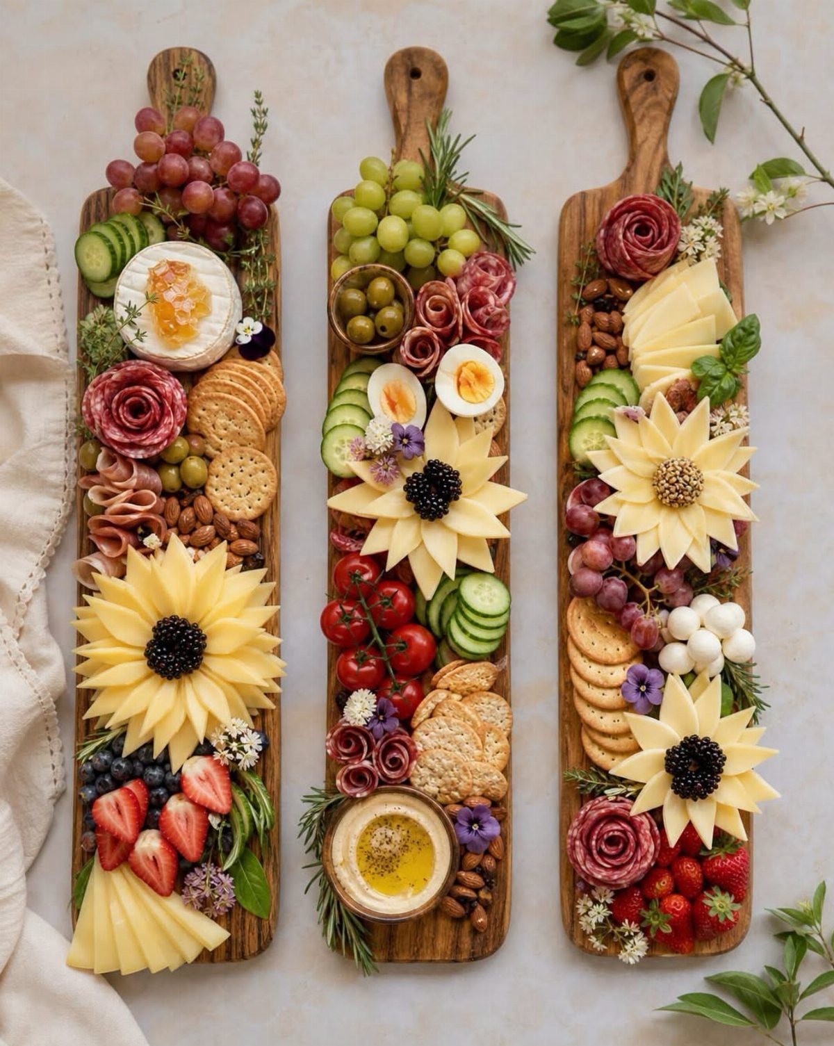 Three wooden charcuterie boards featuring salami roses, cheese sunflowers, and fresh autumn fruits.