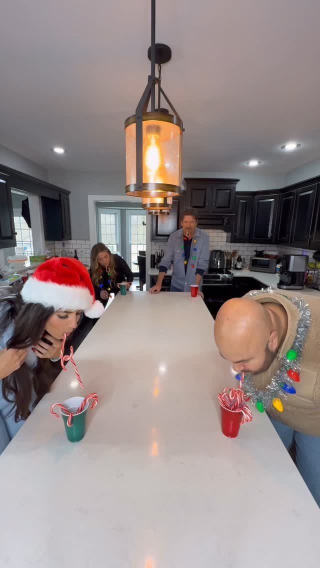 People using candy canes in their mouths to move them into plastic cups.