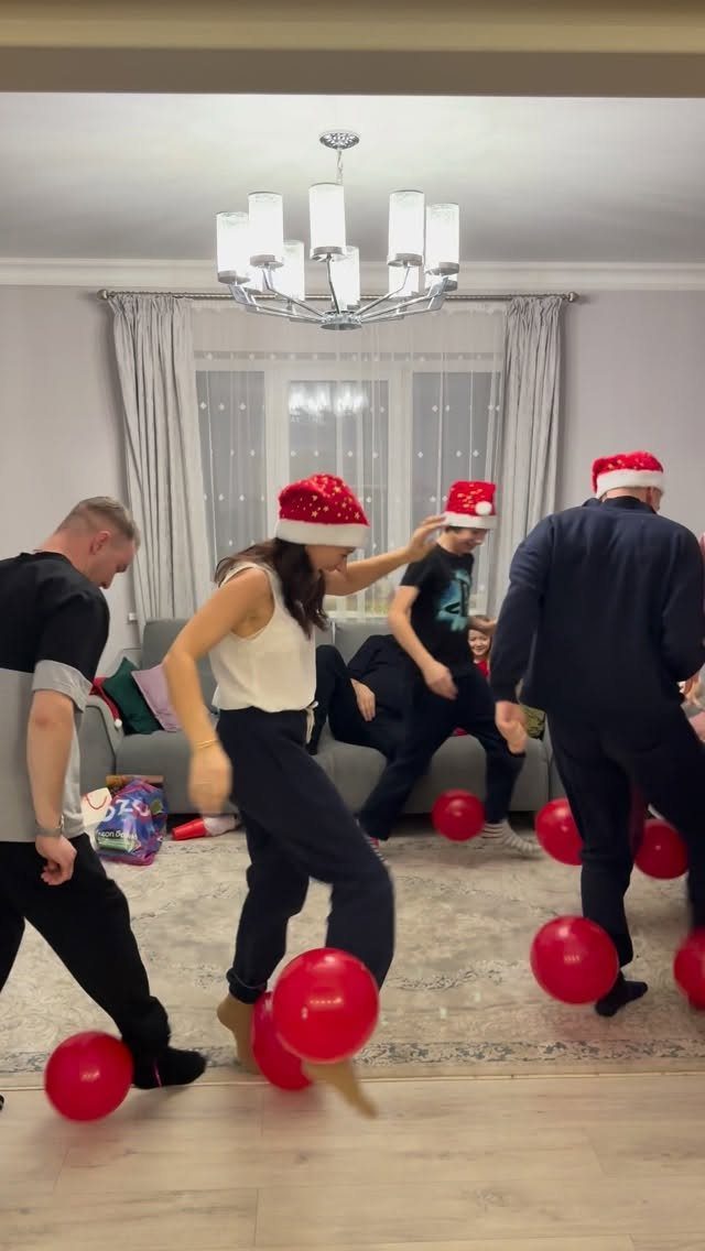 People wearing Santa hats playing a balloon game in a decorated living room