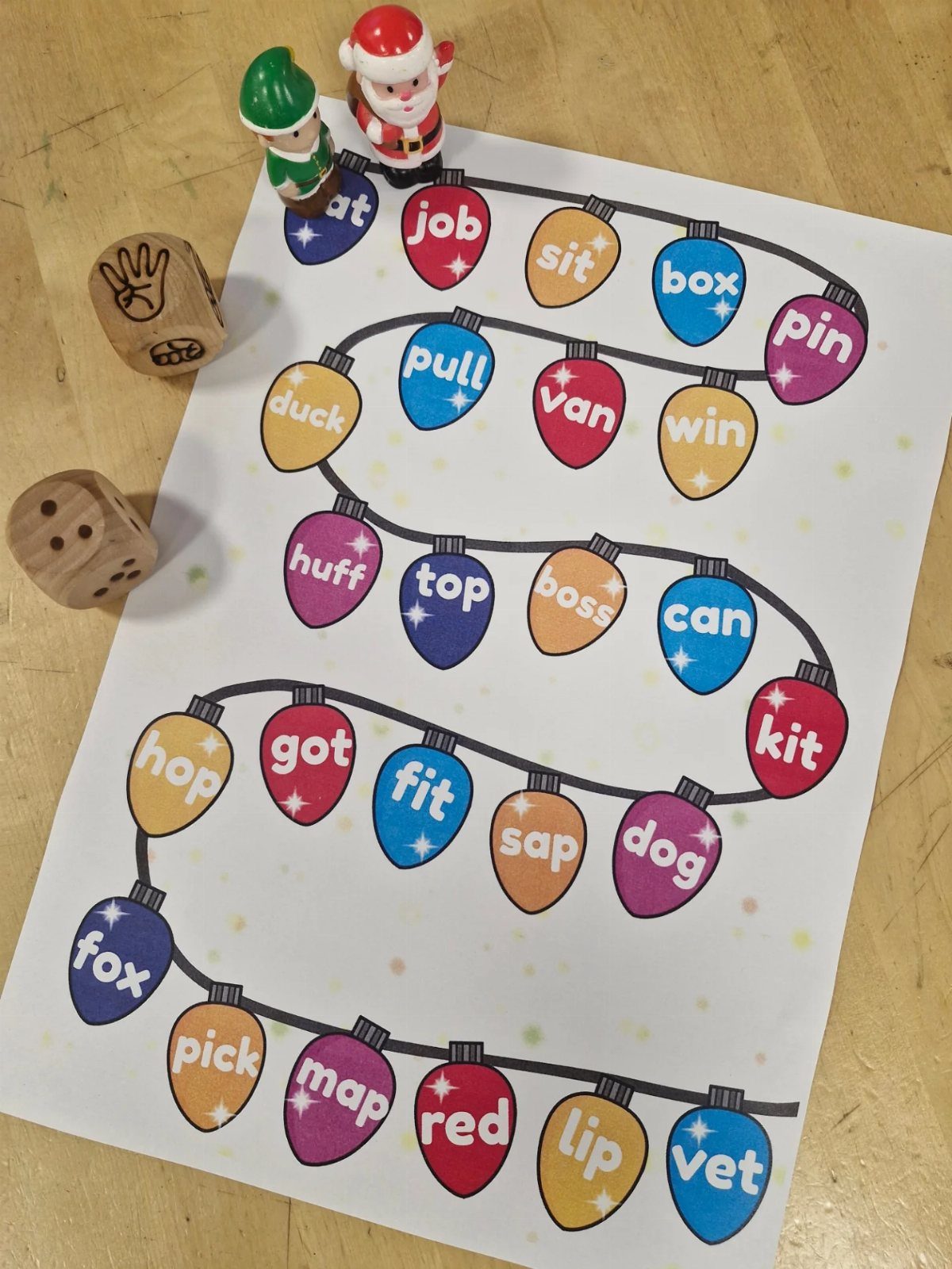 Christmas light bulb board game with Santa and elf figurines on wooden table