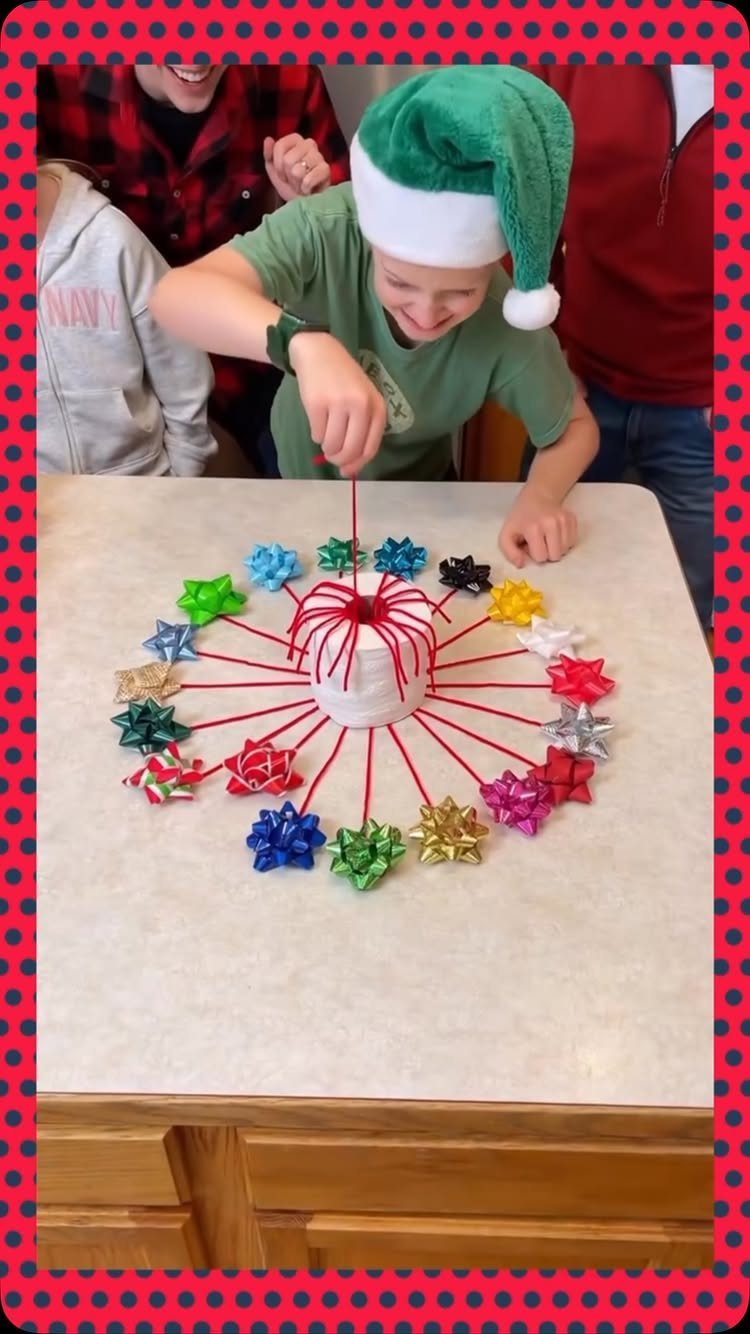Boy in elf hat pulling red strings connected to colorful gift bows on table