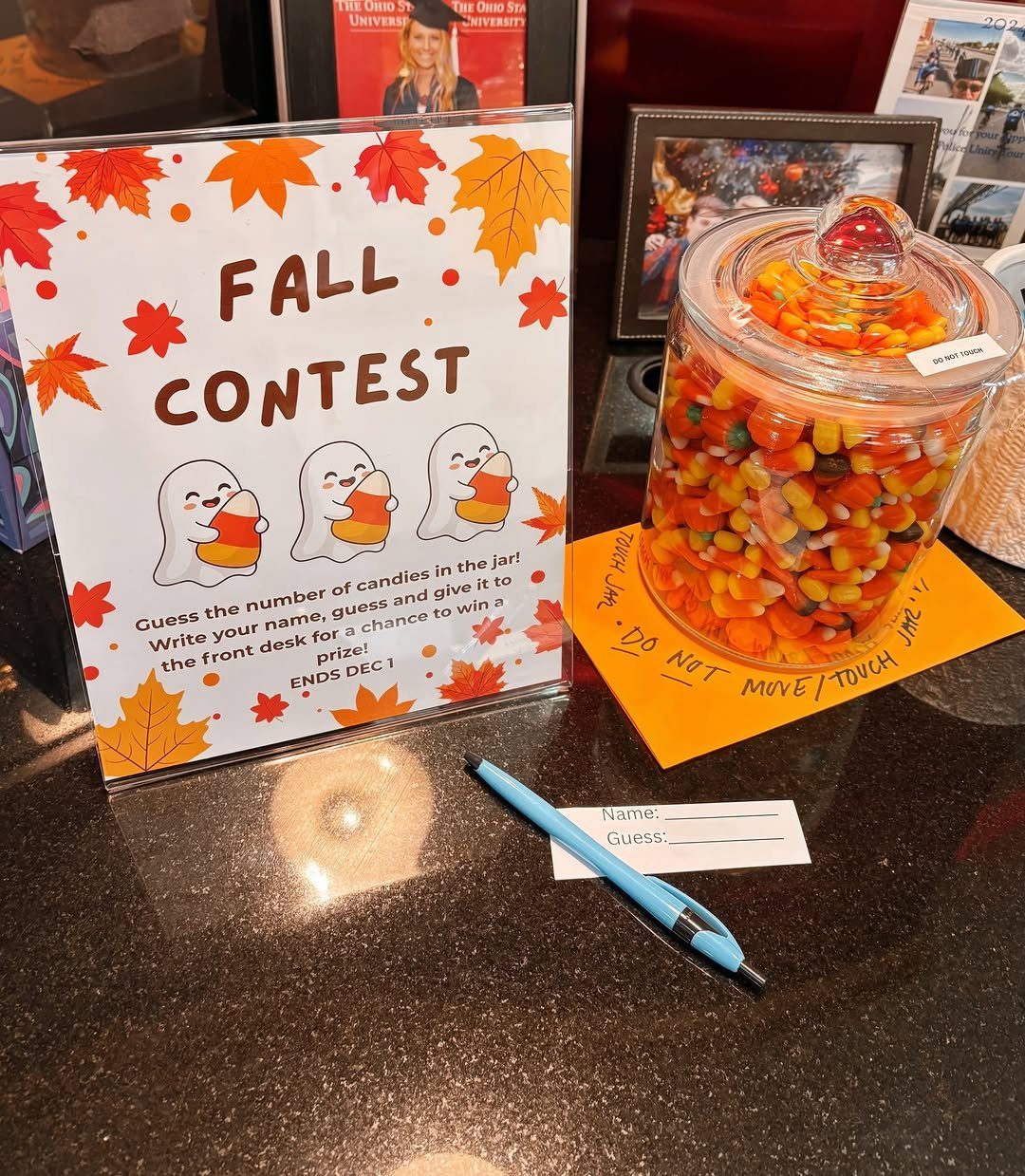 Glass jar filled with candy corn next to a Fall Contest guessing sign.