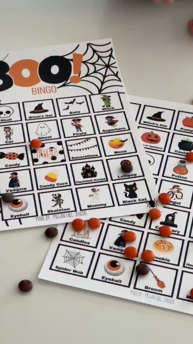 Halloween bingo cards with spooky illustrations and candy pieces used as game markers.