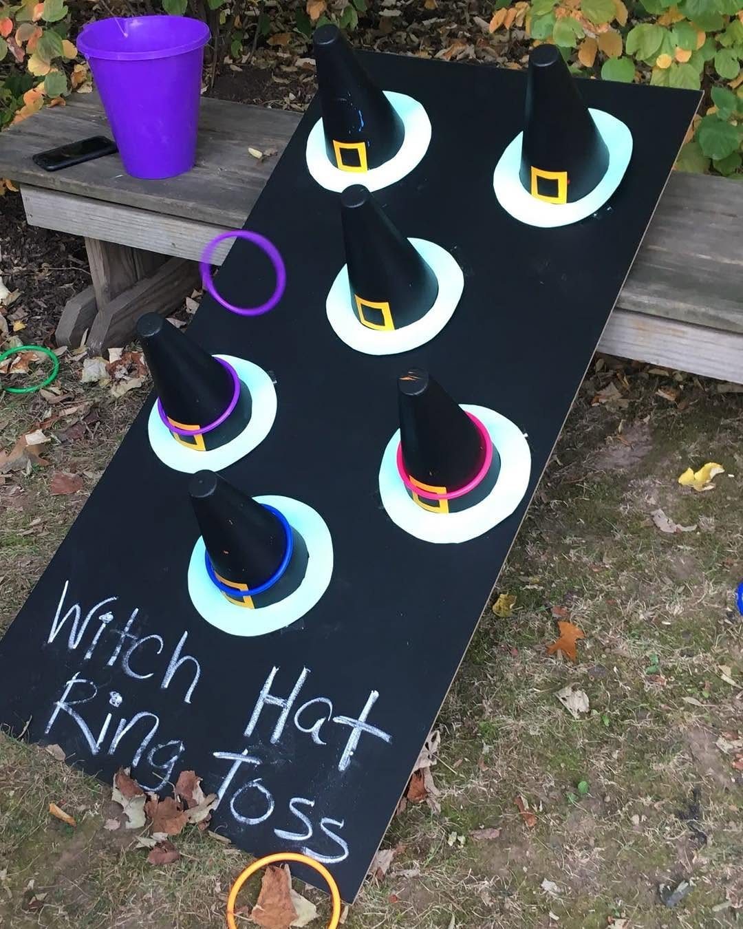 Witch hat ring toss game with black hats on a black board outdoors.