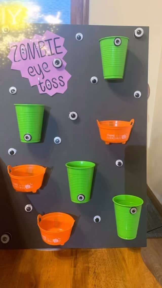 Zombie eye toss game with green and orange cups on a grey board