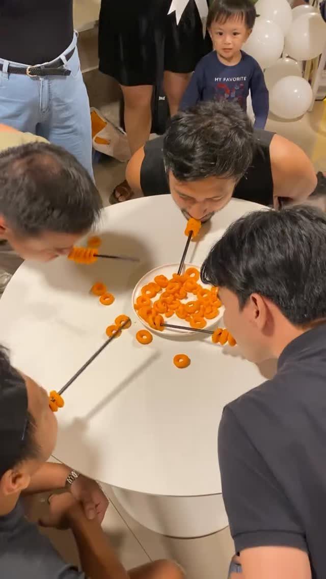 Men using chopsticks in their mouths to eat cereal for a party game