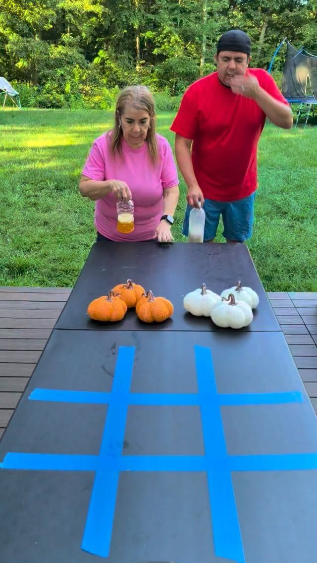 Two people standing behind a table with pumpkins and a blue tape grid.