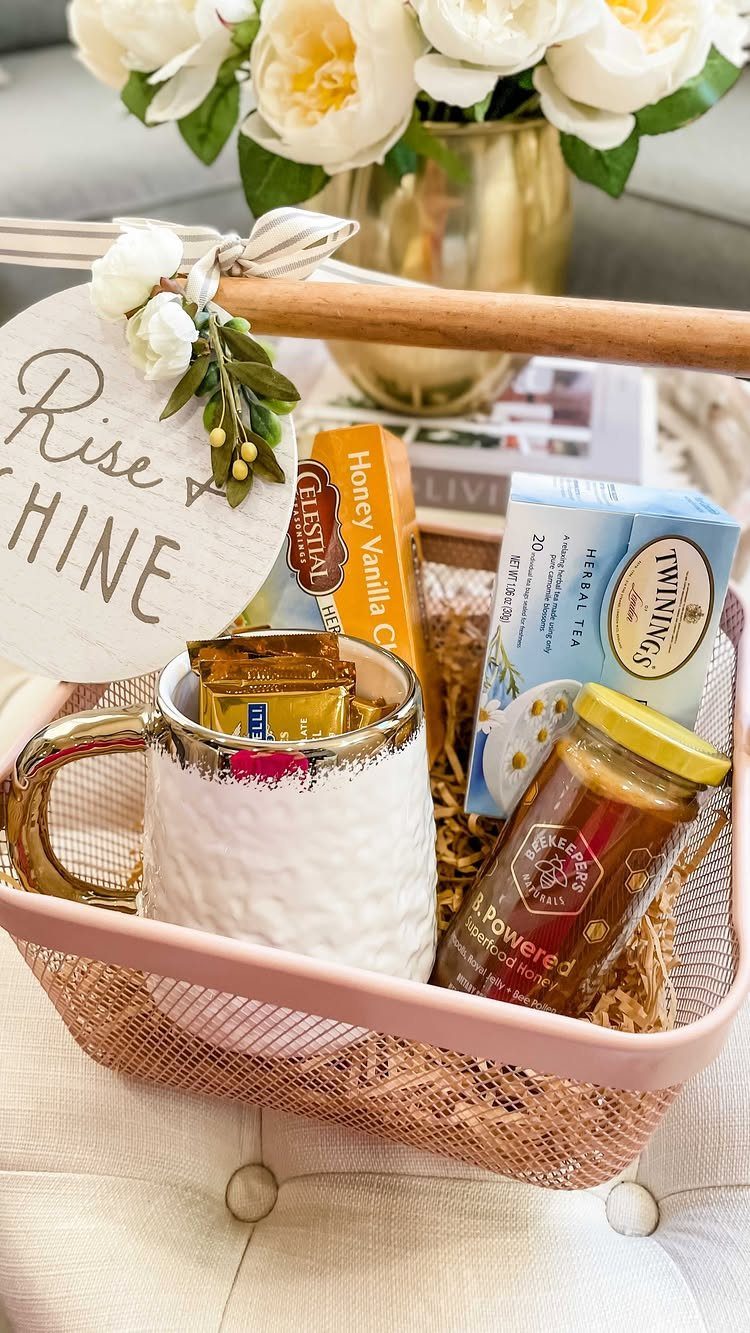 Pink wire gift basket containing tea, honey, a candle, and a white mug.