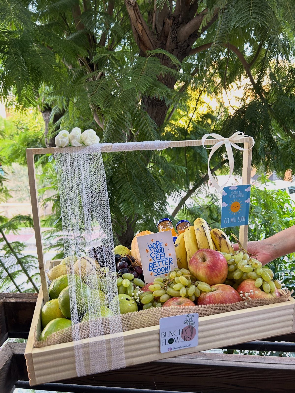 Fruit gift basket with apples, grapes, and bananas in a wooden crate.
