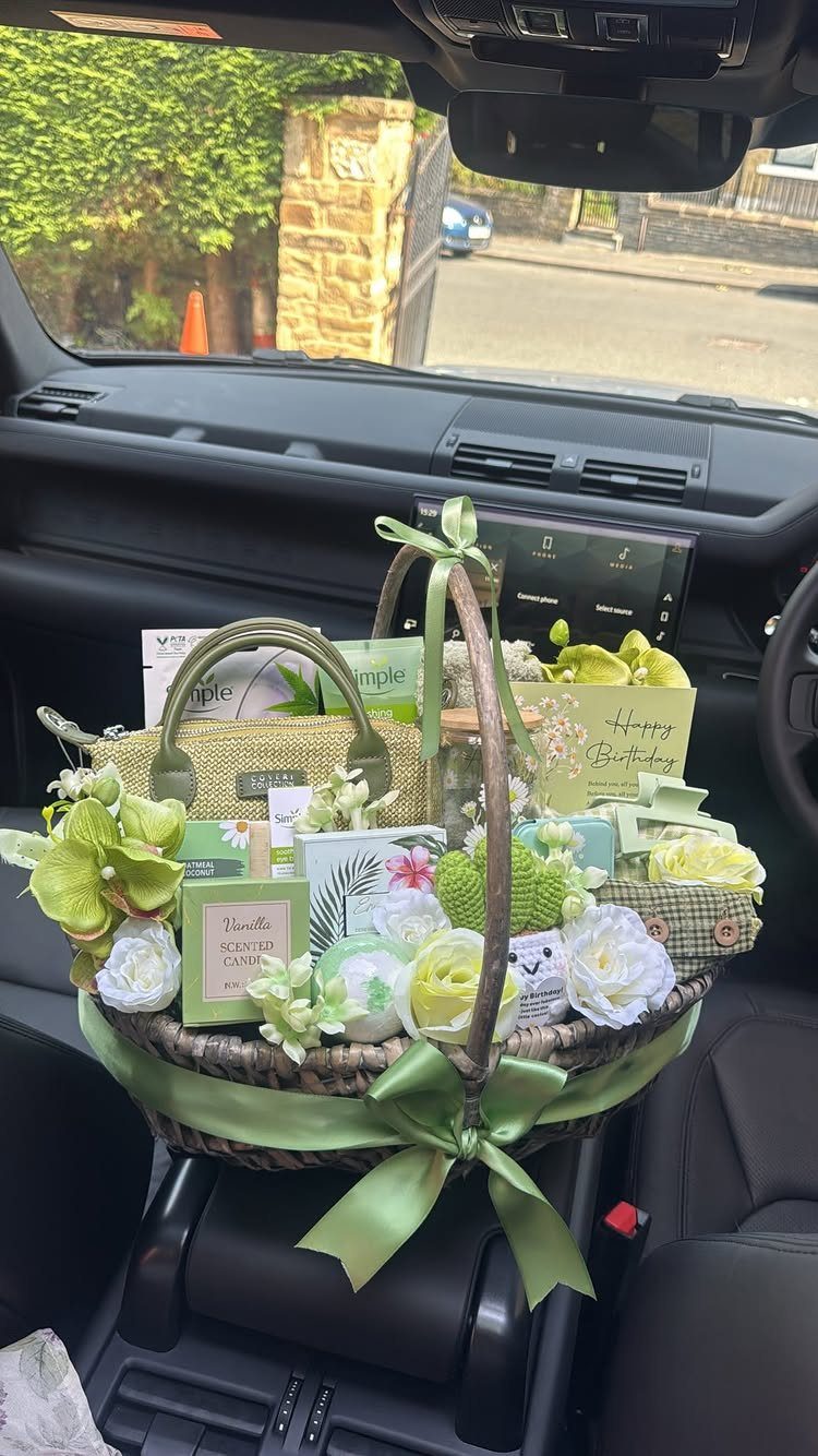 Wicker gift basket with green and white themed products sitting inside a car