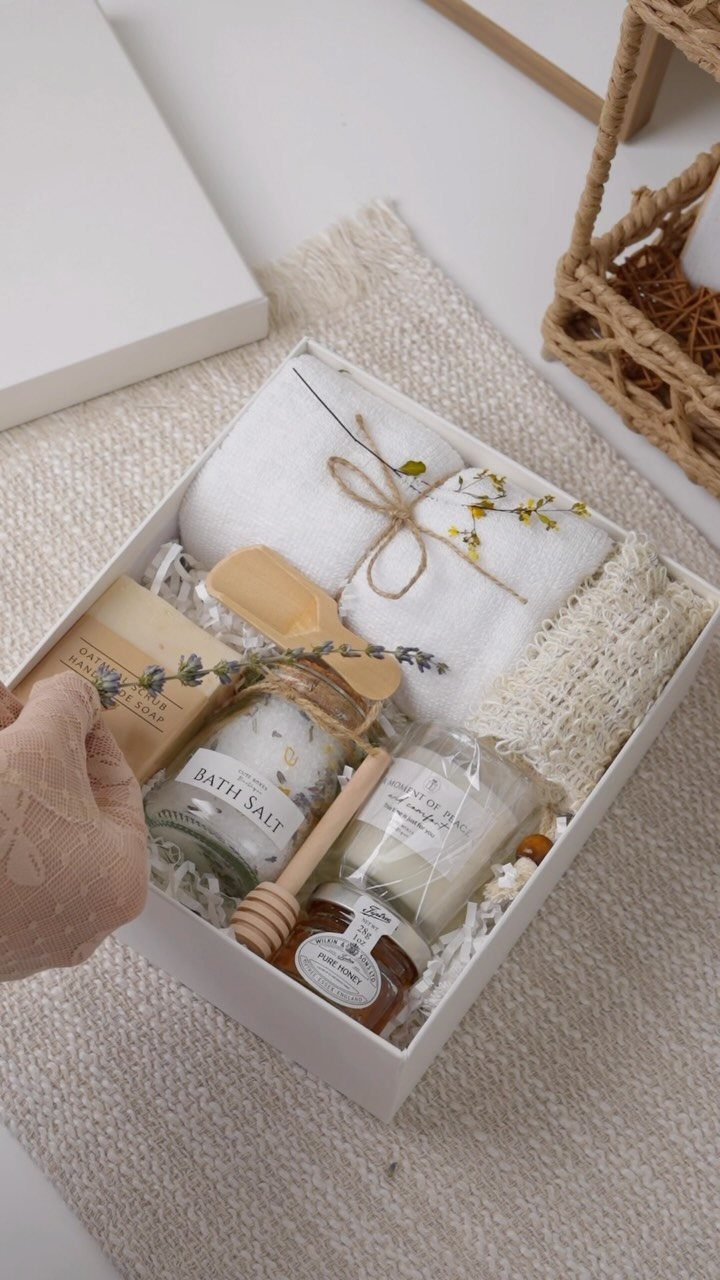White gift box with towels, bath salts, a candle, and honey for spa relaxation.