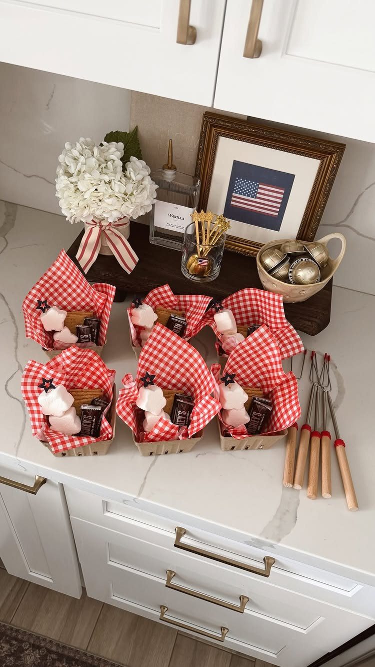 S'mores kits in red checkered baskets with roasting sticks on a white counter.