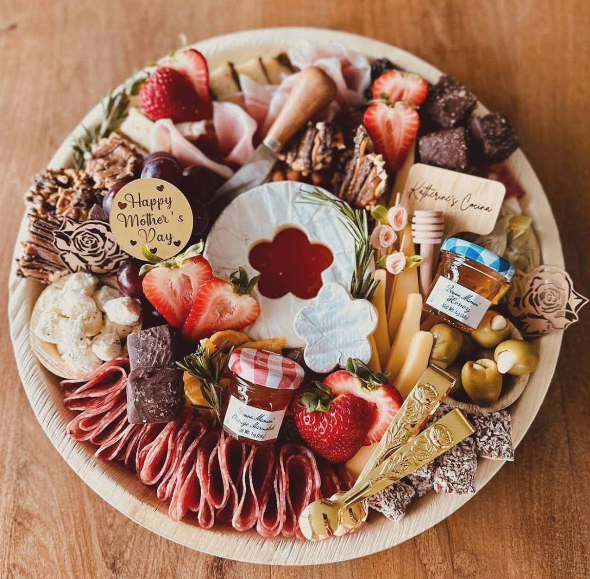 Wooden platter filled with meats, cheeses, fruits, and sweets for Mother's Day.