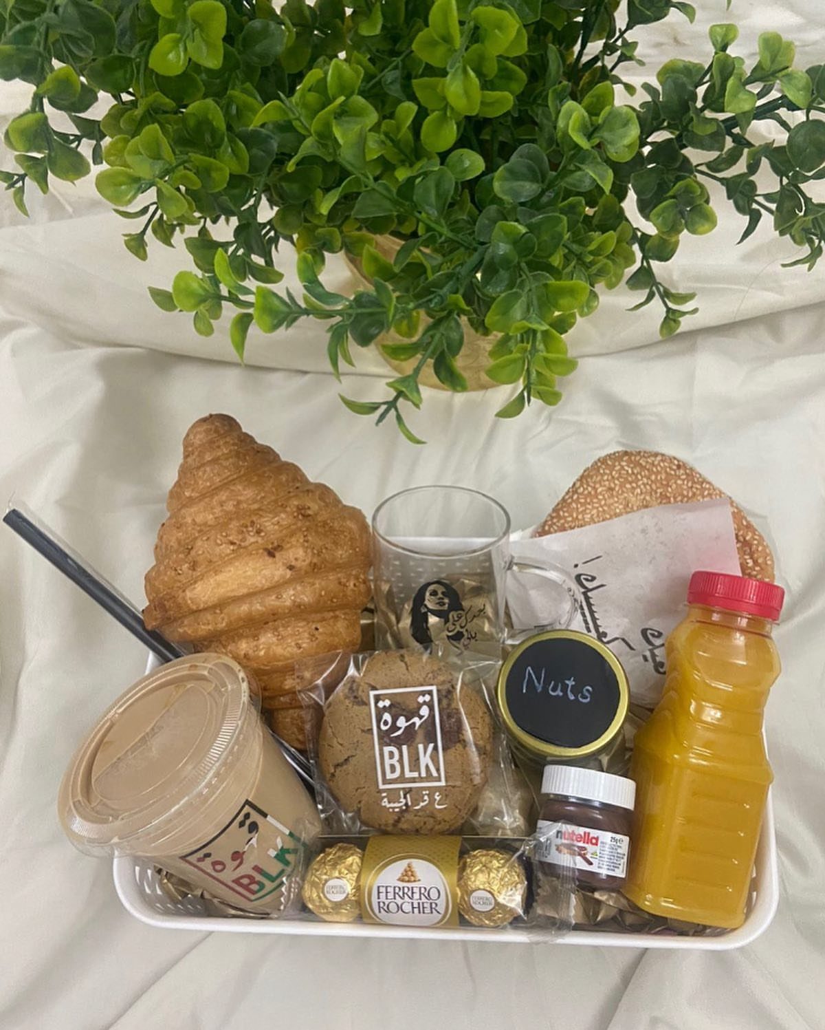 Breakfast gift tray with croissant, bagel, orange juice, coffee, and assorted sweets.