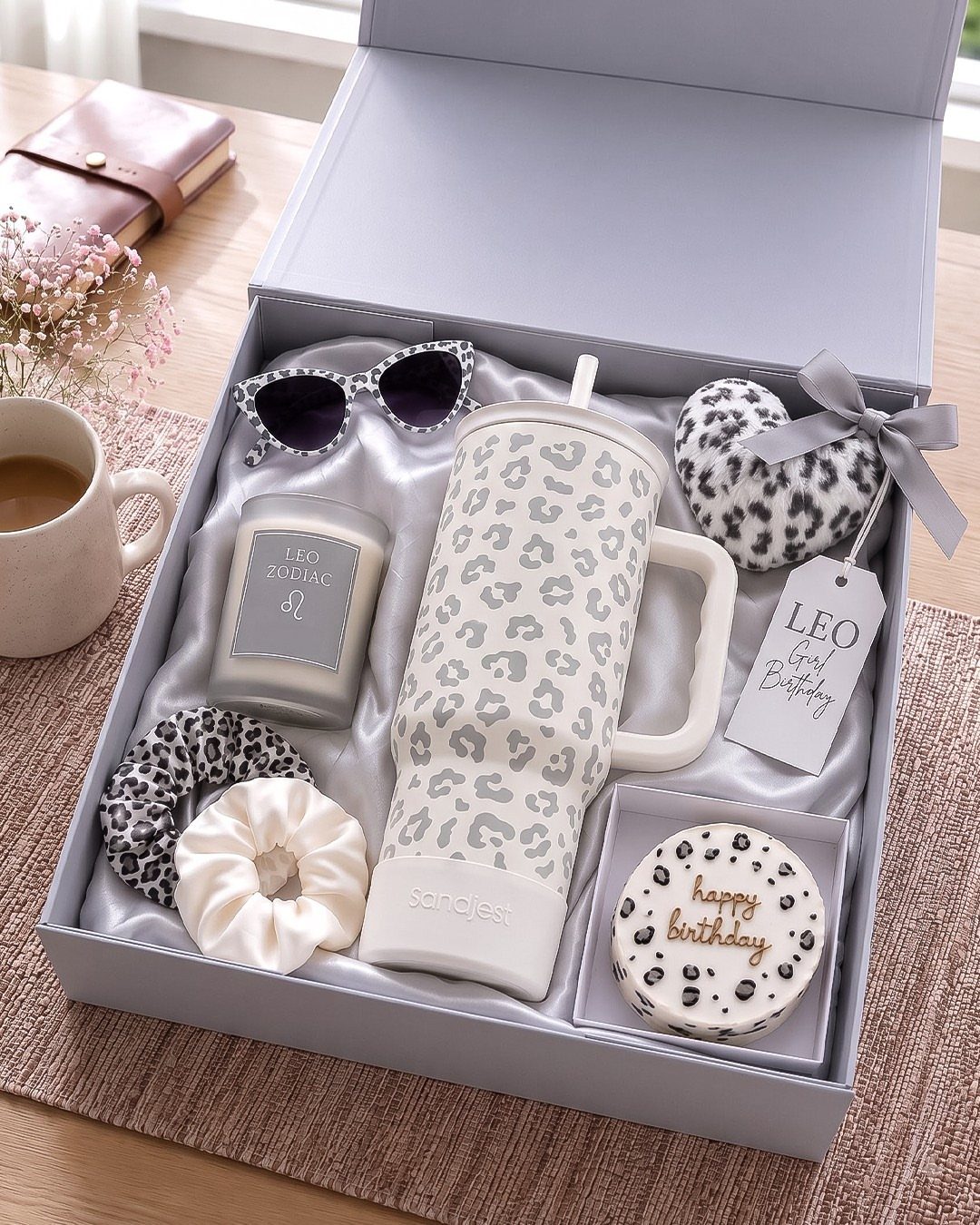 Gift box with leopard print tumbler, candle, and accessories on a wooden table