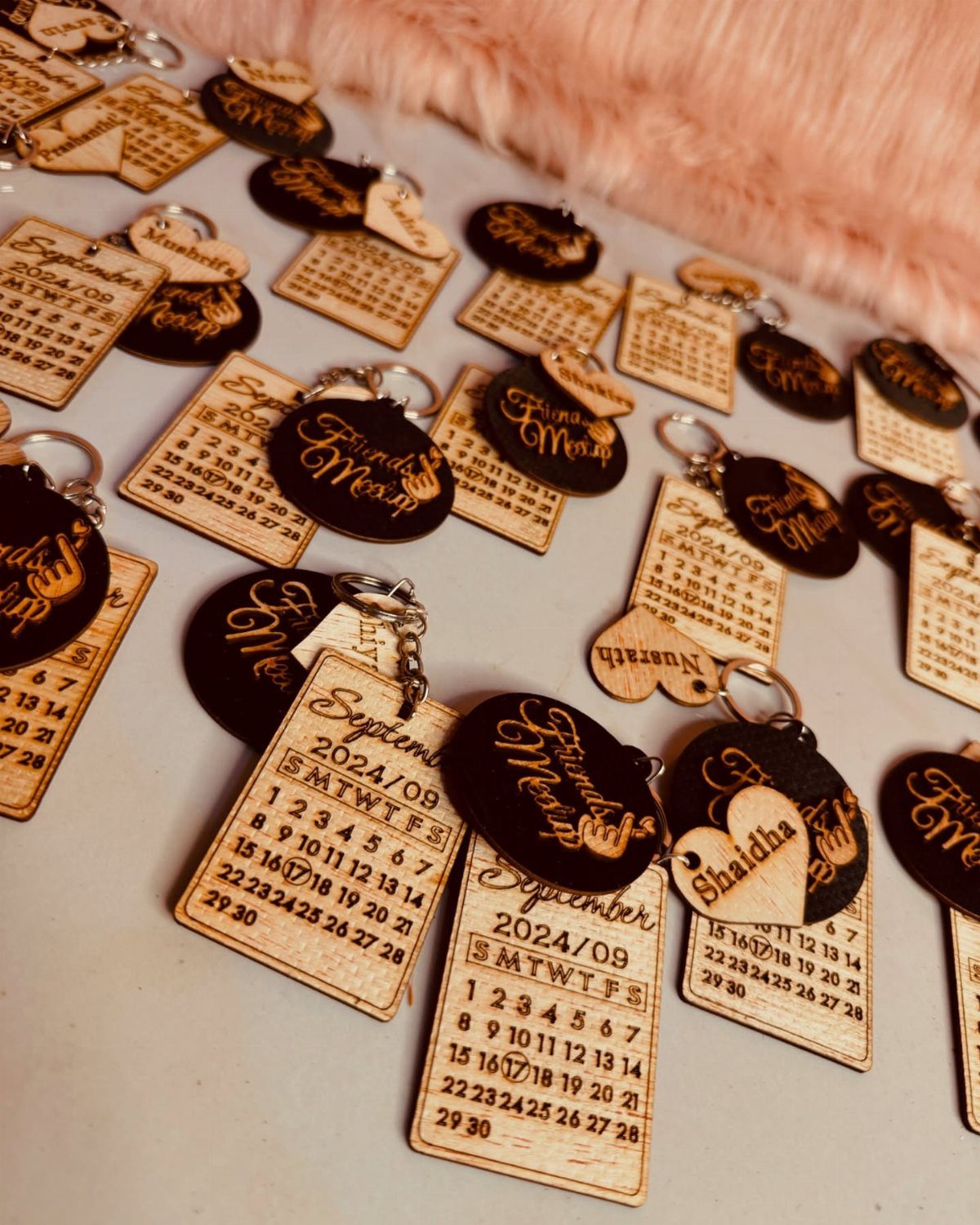 Wooden and black acrylic personalized keychains with calendar dates and gold cursive names.
