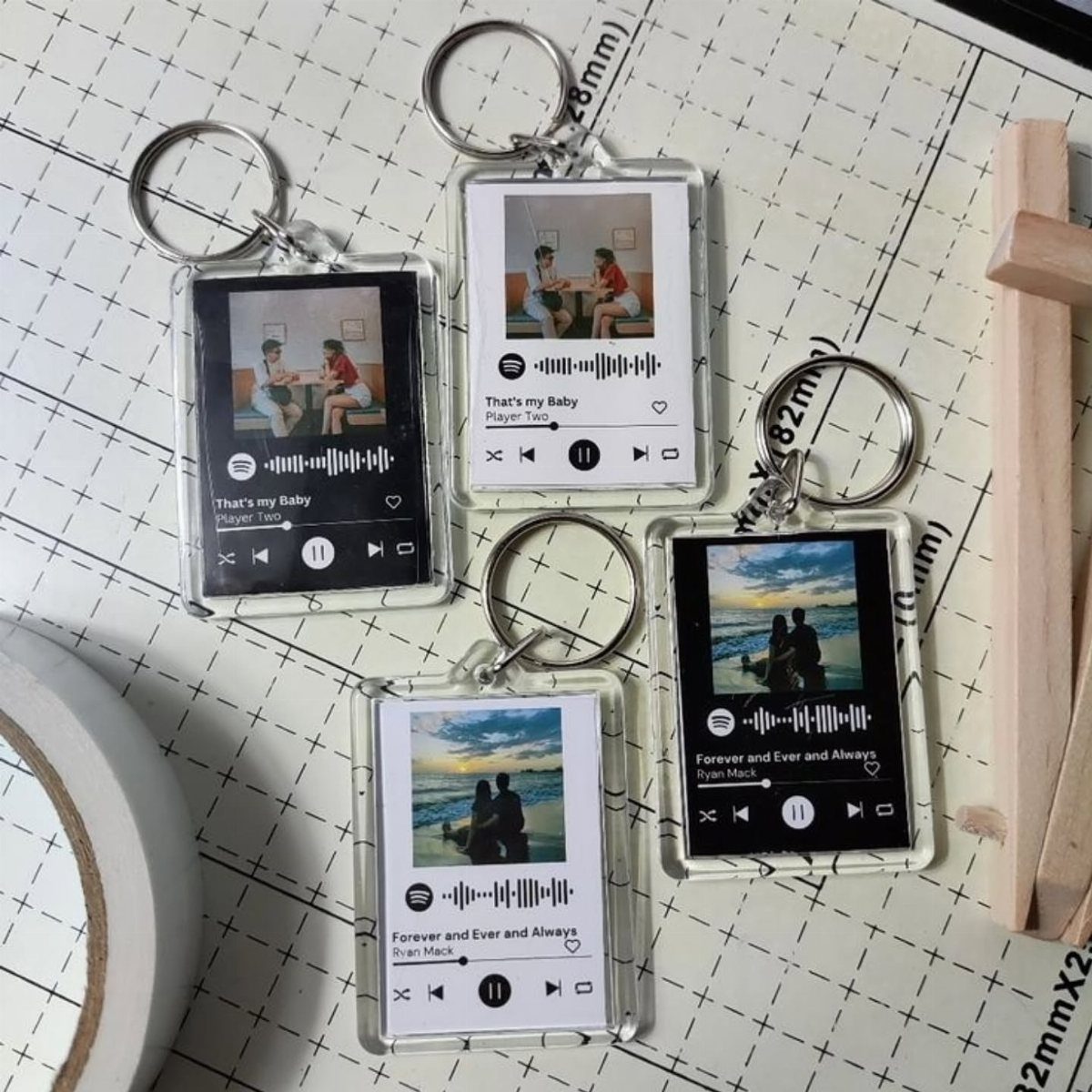 Acrylic music player keychains with custom photos and Spotify codes on a grid mat