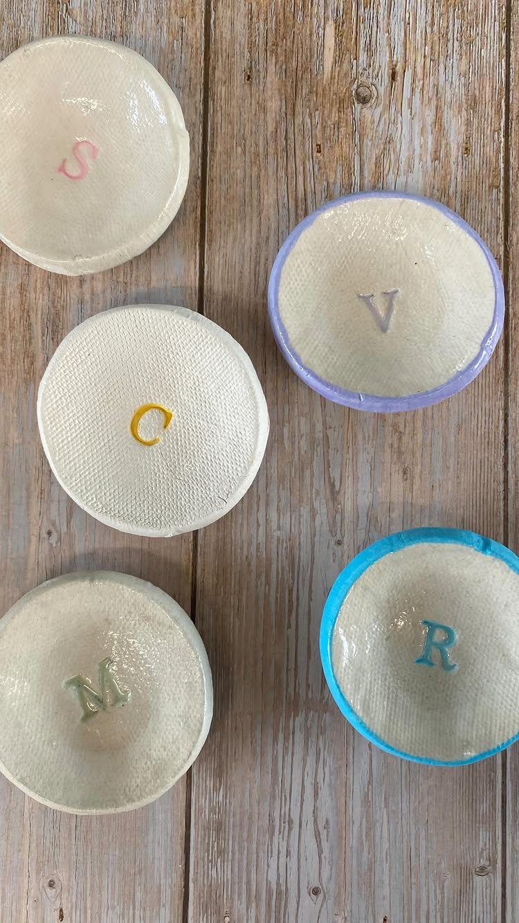 Handmade ceramic bowls with colorful initials on a rustic wooden background