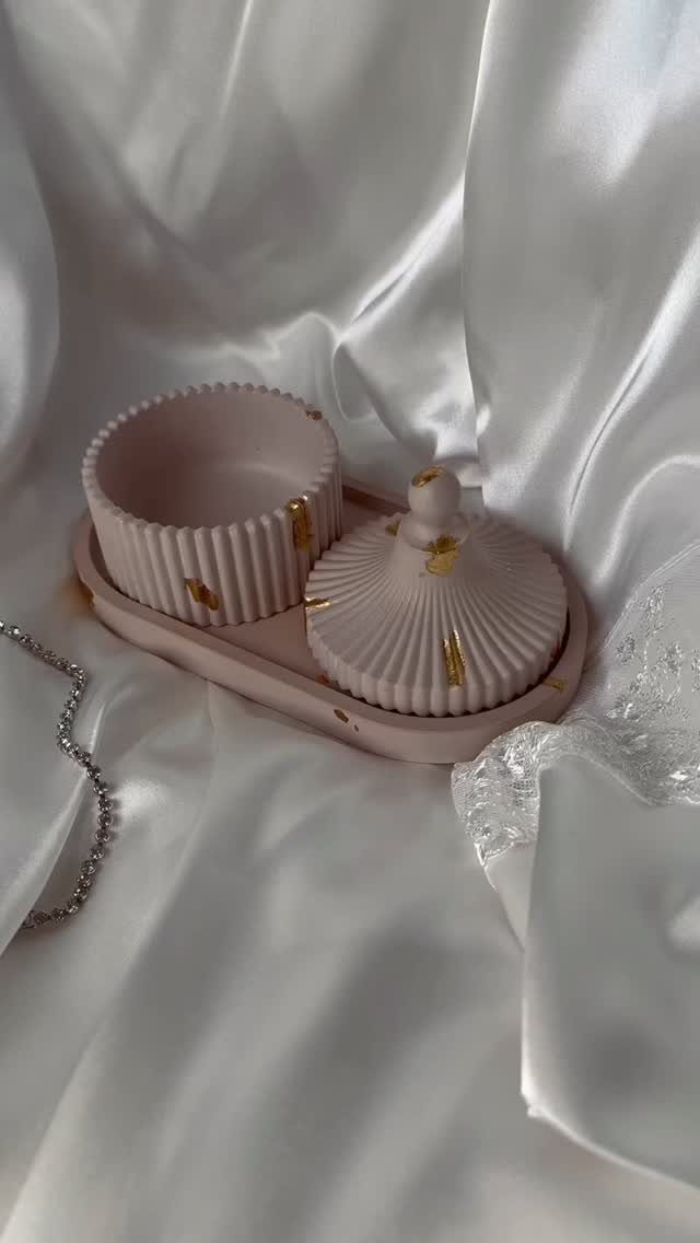 Pink ribbed jewelry tray set with gold accents on white satin fabric