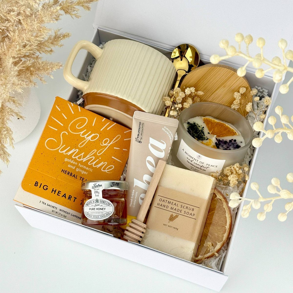 Self-care gift box with herbal tea, ribbed mug, honey, soap, and scented candle.